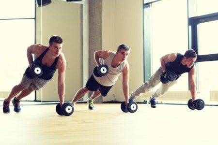 men in gym studio doing push up with dumbells