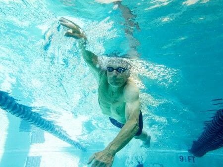 man underwater swimming laps in h2run group class at padonia gym