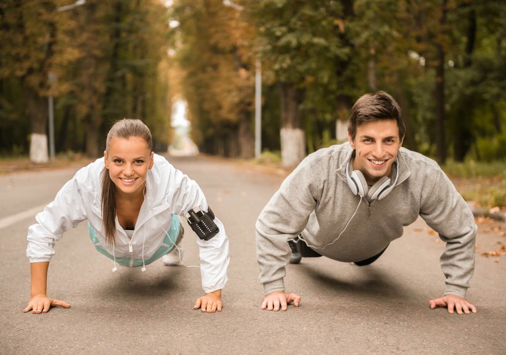couple on street in fall with headphones doing push up