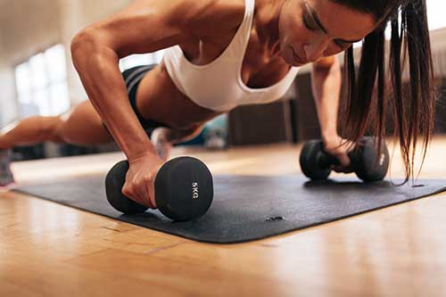 women using weights in plank pose for push ups at gym near me