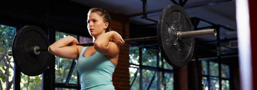 woman at gym holding bench press on shoulders for forward lift