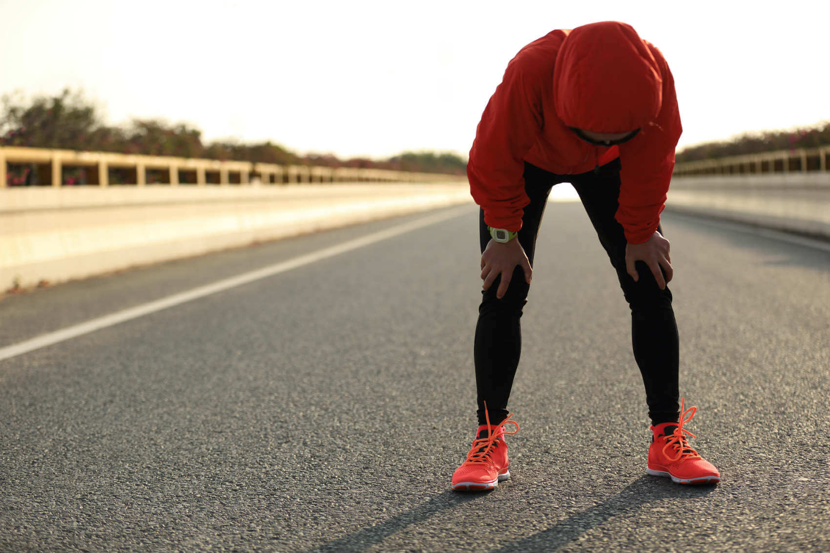 woman resting after run on runners paved path outdoors