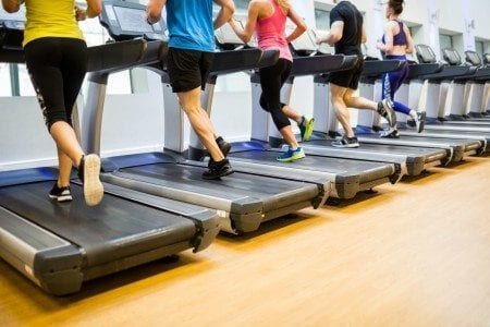 gym members jogging on treadmills at gym