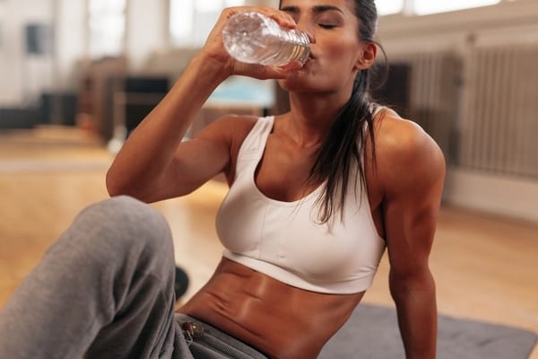 woman hydrating with water post group fitness class at gym