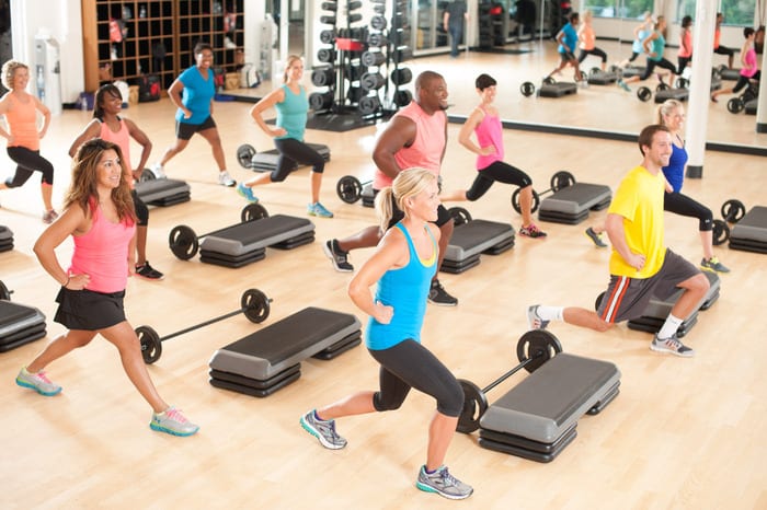 rotunda gym members in bodypump group fitness class squatting