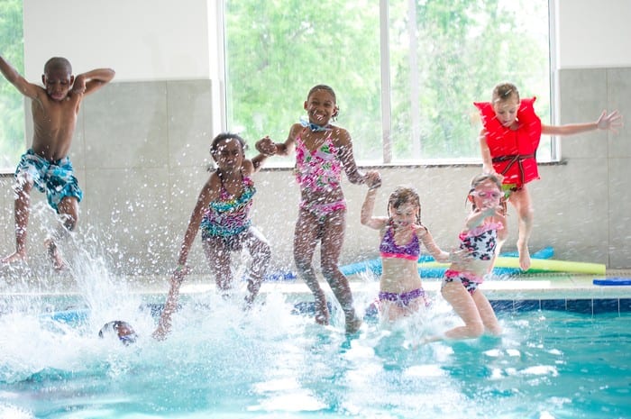 kids swimming splashing and jumping in pool in padonia gym at birthday party