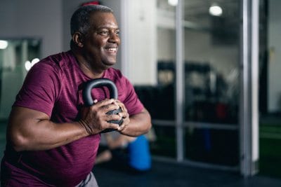 fitness member holding kettlebell while working out in brick bodies gym