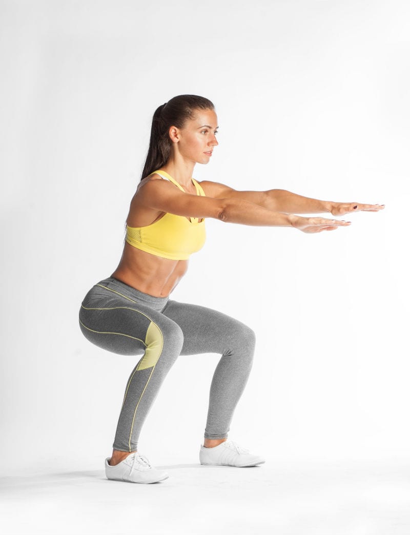 woman in fitness attire demonstrating proper body mechanics when squatting from brick bodies reistertown md squats