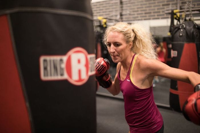 woman at rotunda gym with boxing gloves punching boxing bag