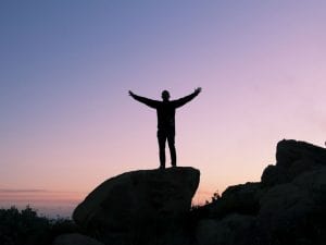 man on rock with arms outstretched proud to have completed intense workout at brick bodies padonia md gym