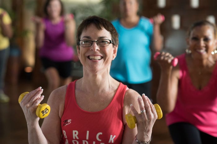 happy brick bodies senior fitness class member using weights to exercise at gym in reistertown