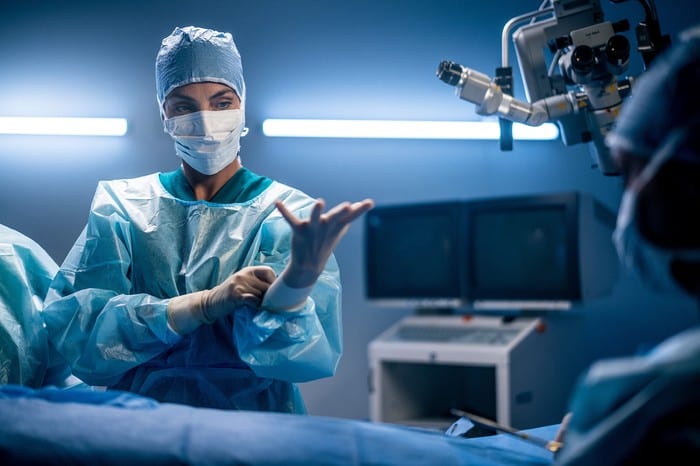 female surgeon putting gloves on in operating room