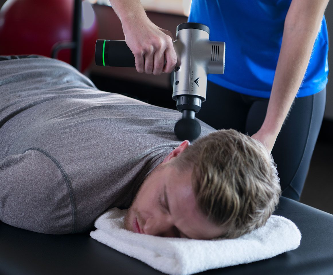 Man receiving massage gun therapy