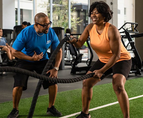Personal trainer with woman working out with ropes