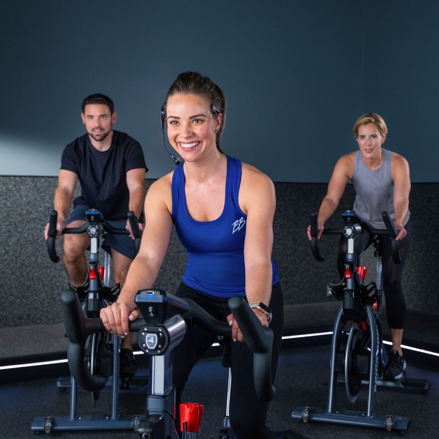 Woman smiling while spinning in indoor cycling class at gym