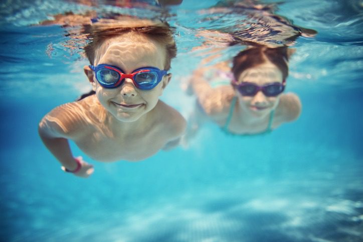 Happy kids swimming underwater in pool