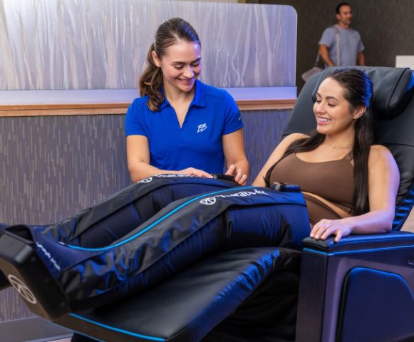 a recover team member assists a gym member with compression therapy during a recovery session at brick bodies gym in padonia