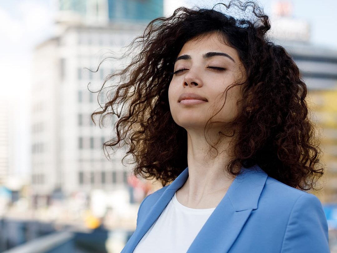 Businesswoman relaxing outdoor with deep breathing techniques