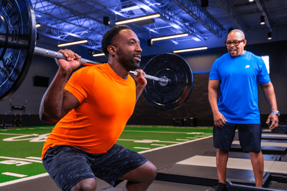 personal trainer and client training barbell squats